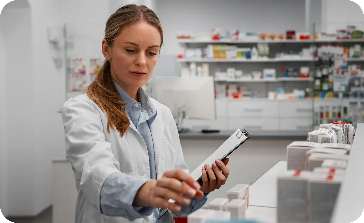 Pharmacist checking stock on the pharmacy shelves with a clipboard