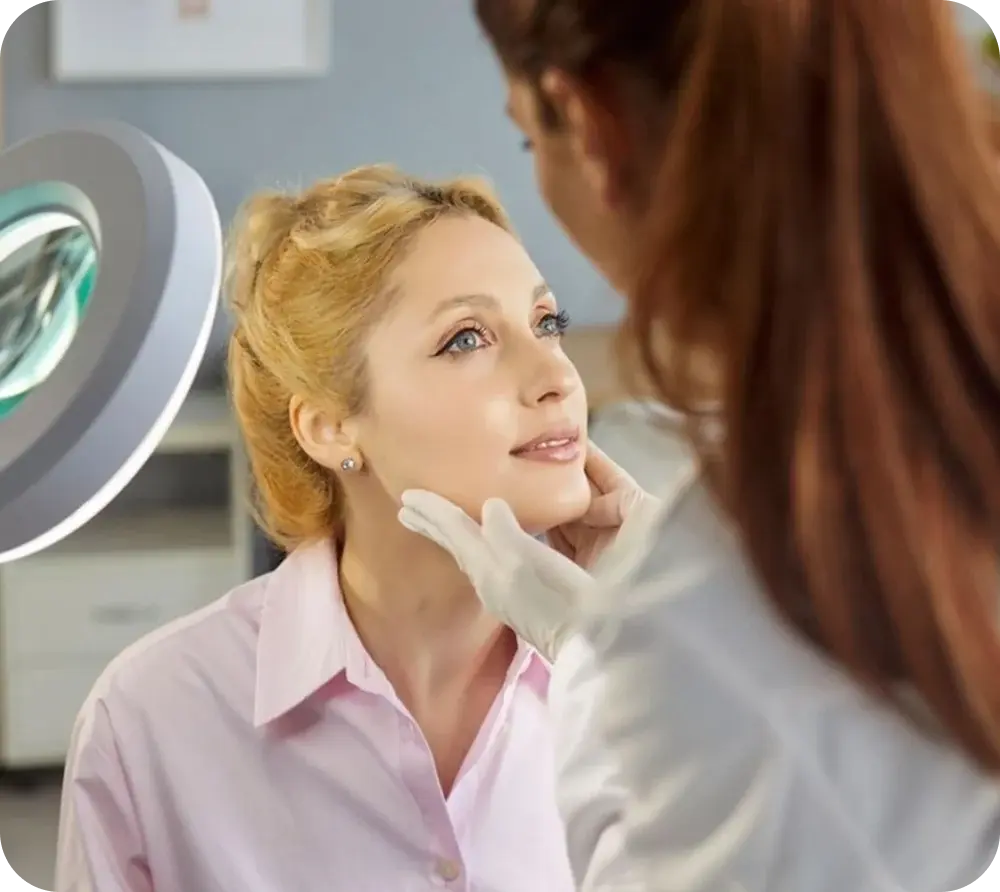 Dermatologist examining a patient’s skin with a magnifying lamp